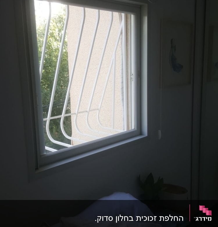 חלון זכוכית עם סורגי מתכת לבנים